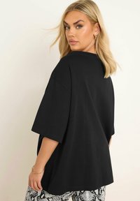 Svart oversized t-shirt med korta ärmar. Slät tyg, avslappnad passform och rundad halsringning. Bärs tillsammans med mönstrade byxor av ormskinn.