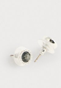 Orecchini a bottone in argento con rhinestones centrali scuri circondati da piccoli cristalli trasparenti, mostrati con retro trasparente su una superficie bianca.