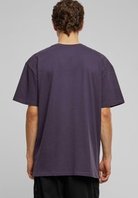 T-shirt à manches courtes en coton, de couleur violette, avec une coupe décontractée. Encolure ronde, ourlet cousu et sans logo ni motifs visibles.