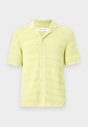 Lime zaļš īsām piedurknēm adīts krekls ar teksturētu ģeometrisku rakstu, klasiskas apkakles un pogu aizvēršanu, izgatavots no mīksta auduma.