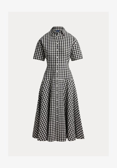 Juoda ir balta languota suknelė trumpomis rankovėmis, aptemptu liemeniu ir platėjančia sijono dalimi. Suknelė turi priekyje sagas ir klasikinius apykaklės elementus.