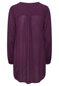 Långärmad blus i djup lila, med rak skärning, mjuk textur och plisserad detalj på baksidan. Knappar på ärmarna förbättrar designen.