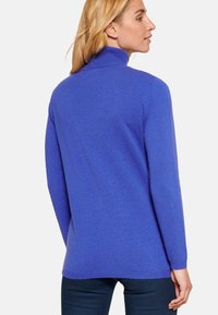 Maglione a collo alto blu royal con maniche lunghe, realizzato in un morbido tessuto a maglia. Presenta una linea dritta e rifiniture a costine nei polsini e all'orlo.