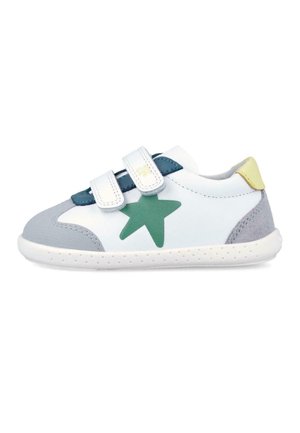 Zapatilla blanca para niños con estrella verde, detalles en gris y amarillo, y dos tiras de velcro blancas sobre una suela blanca.