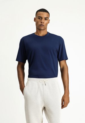 Camiseta de manga corta azul marino con cuello redondo, combinada con pantalones texturizados gris claro que cuentan con una cinturilla elástica y cordón ajustable.