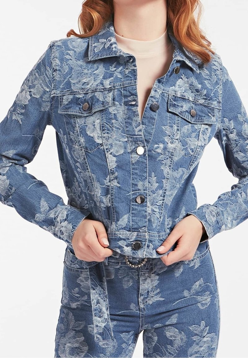 Giacca in denim con motivo floreale, colore azzurro chiaro, due tasche sul petto, bottoni a pressione e dettagli con vita rifinita.