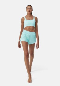 Lichtblauwe sportbeha en bijpassende shorts, beide van een gladde, elastische stof. Vierkante halslijn en elastische tailleband voor comfort.