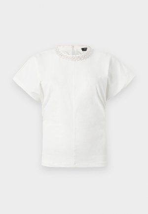 Λευκό μπλουζάκι με κοντά μανίκια, διακοσμημένο γιακά με μαργαριτάρια και κλείσιμο με κουμπί στο πίσω μέρος, παρουσιασμένο σε απλό φόντο.