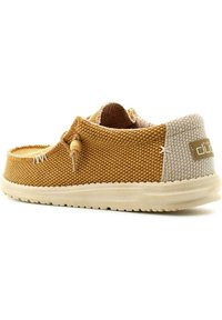 Scarpa in tessuto intrecciato beige con accenti color sabbia, forma rotonda, superficie testurizzata, lacci elasticizzati con toggle in legno e suola imbottita.