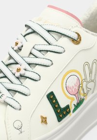 Sneaker sintetico bianco con accenti verdi e rosa, caratterizzato da hardware decorativo in oro, serragli in forma di fiore e grafiche colorate ricamate.
