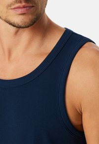 Marineblauwe geribbelde tanktop met een ronde halslijn, brede schouderbanden en een gestructureerde stof die de lichaamscontouren benadrukt.