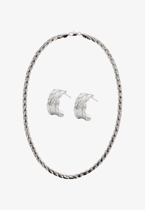 Ezüst fém nyaklánc csavart lánc kialakítással, texturált ezüst karika fülbevalókkal párosítva, absztrakt formával.