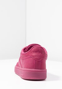 Baskets Reebok roses vues de l'arrière avec des logos en relief sur le talon et la semelle, placées sur un fond blanc uni.