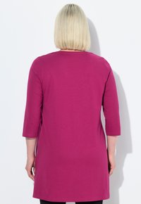 Fuchsia-Tunika mit Dreiviertelärmeln, aus einem weichen Stoff gefertigt. Einfaches Design mit geradem Schnitt, reicht bis zur Mitte des Oberschenkels.