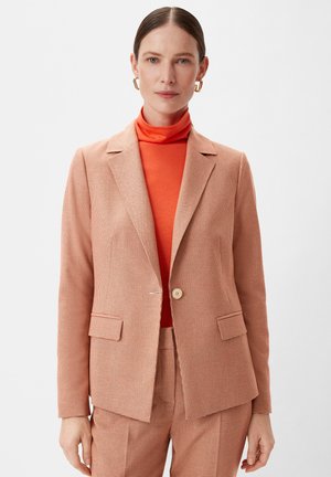 Blazer à carreaux pêche avec un col à revers, fermeture à un bouton et deux poches avant, superposé sur un col roulé orange.