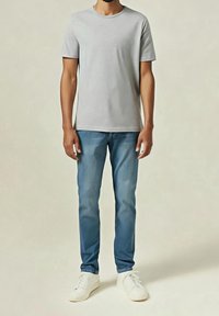Světle šedé tričko s krátkým rukávem v kombinaci se světlými modrými džínami a bílými teniskami. Tričko má kulatý výstřih a hladkou texturu.