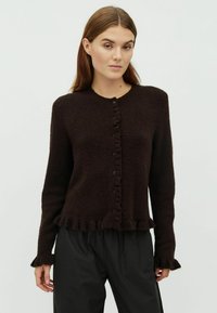 Barna, kötött kardigán kerek nyakkivágással, elöl gombos záródással és fodros részletekkel az alján és az ujjaknál. Puha anyag és testhez álló fazon.