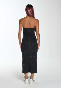 Abito midi nero senza spalline con una sottile texture a motivo; presenta una silhouette aderente. Abbinato a sneaker bianche.