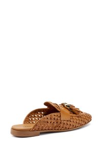 Sandalo slip-on in cuoio intrecciato color testaan, con punta arrotondata, dettaglio con nappe e suola piatta minima. Design con retro aperto per una facile calzabilità.