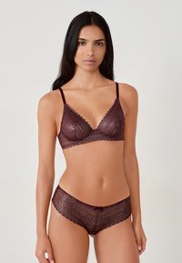 Bordeaux kanten bralette met gegolfde randen en verstelbare bandjes, gecombineerd met bijpassende kanten boyshorts met een kleine strikaccent.