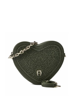 Bolso de mano en forma de corazón de color verde oscuro con patrón perforado floral y correa de cadena en tono dorado con detalle de logotipo en el frente.