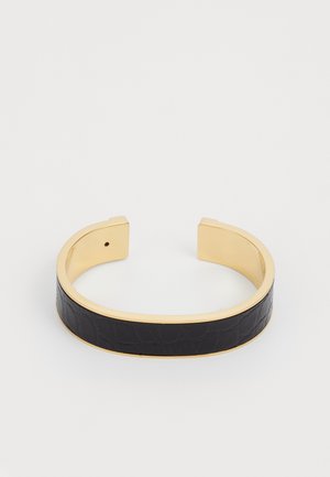 Cuff bracelet featuring a gold metal frame and a textured black leather band in the center, with open ends and a minimalist design.