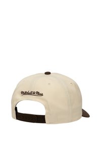 Casquette crème avec une visière marron et une fermeture snapback marron. Présente le logo "Mitchell & Ness" brodé en marron à l'arrière.