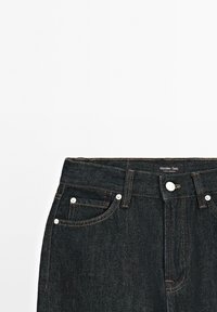 Donker denim jeans met hoge taille, voorzien van vijf zakken, contrasterende stiksels en een merklabel op de tailleband.