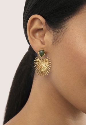 Pendientes de oro con una piedra verde en forma de triángulo y un diseño de estallido solar con picos alargados, que muestran un detalle y una textura intrincados.