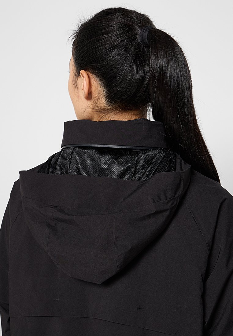 Schwarze wasserdichte Jacke mit Kapuze, ausgestattet mit einem Mesh-Futter und einem eleganten, stromlinienförmigen Design. Sichtbare Nähte auf der Rückseite.