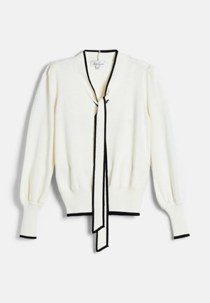 White long-sleeve sweater with black trim on cuffs, hem, and neckline, featuring a black-bordered tie hanging down the front center.