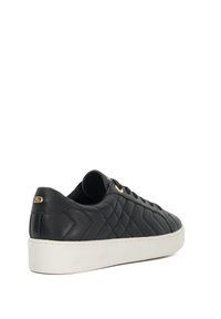 Black leather sneaker with quilted pattern, white rubber sole, and gold eyelets. Side view shows rounded toe and logo detail on heel.