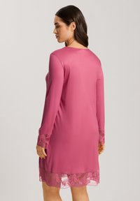 Abito rosa con maniche lunghe, caratterizzato da dettagli in pizzo ai polsini e all'orlo, tessuto liscio e scollatura rotonda. Design semplice ed elegante.