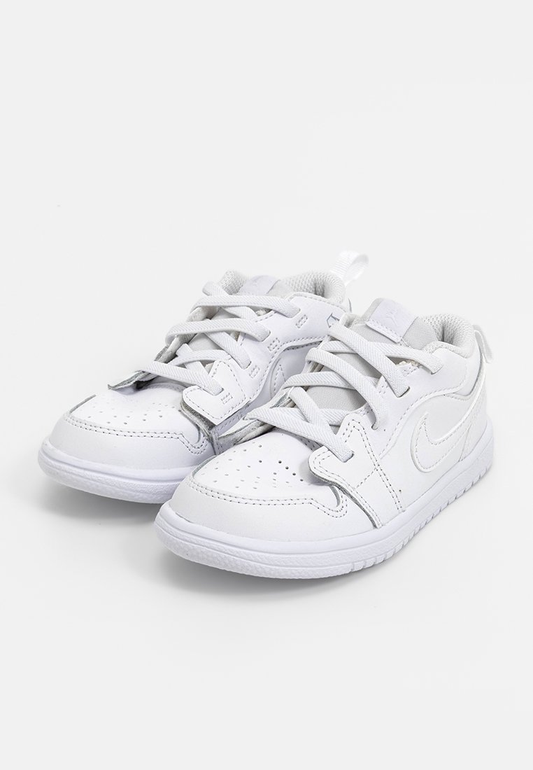 Zapatillas de cuero blanco con punteras redondas, detalles perforados y cordones planos. Presentan una suela de goma texturizada y un sutil logo de Nike.