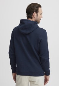 Sudadera azul marino de algodón suave, con capucha ajustable y puños acanalados, con una textura lisa y sencilla y un corte relajado.