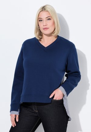 Felpa blu navy con scollatura a V, caratterizzata da maniche lunghe e un'accortezza di tessuto a righe all'orlo e ai polsini. Materiale morbido, vestibilità comoda.