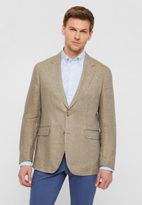 béžový ľanový blazer s dvoma prednými vreckami a zapínaním na jeden gombík, kombinovaný s svetlomodrou košeľou s golierom.
