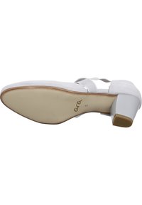 Light gray suede shoe with a closed toe, elastic straps, and a medium block heel. Features a smooth sole and logo on the bottom.