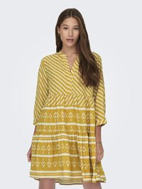 Žuta haljina s uzorkom i V-izrezom te rukavima do tri četvrtine. Sadrži horizontalne i vertikalne bijele pruge te geometrijski uzorak na suknji.