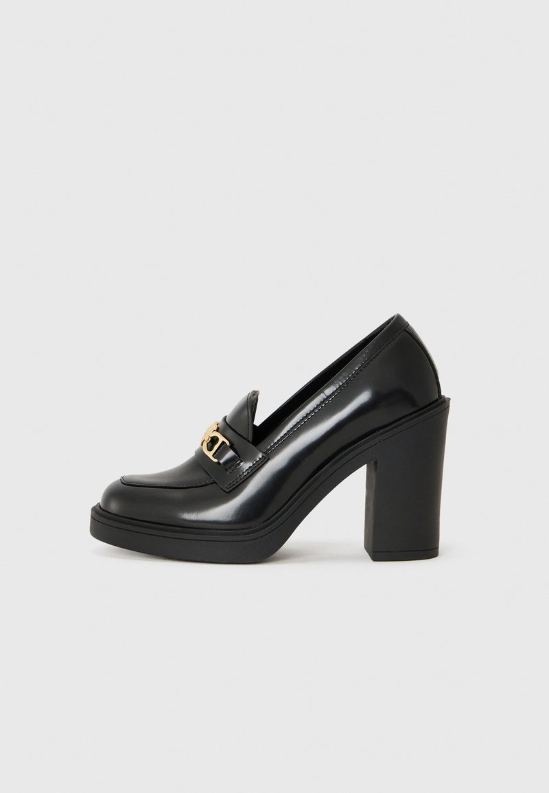 Mocassins à plateforme en cuir verni noir avec un haut talon bloc et des accents en métal doré. Texture lisse et design à bout arrondi.