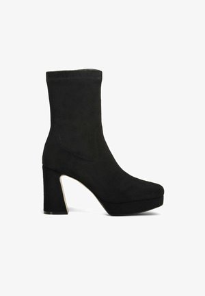 Stivaletti alla caviglia in suede nero con tacco a blocco alto, suola piattaforma e parte superiore senza cuciture. Texture liscia con dettagli di cucitura sottili.