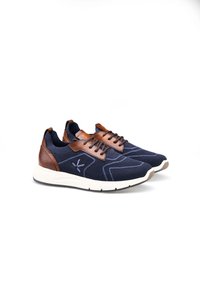 Marineblaue Sportschuhe mit Stricktextur, braunen Lederakzenten und einer weißen Sohle; verfügen über ein geometrisches Muster und Schnürsenkel.