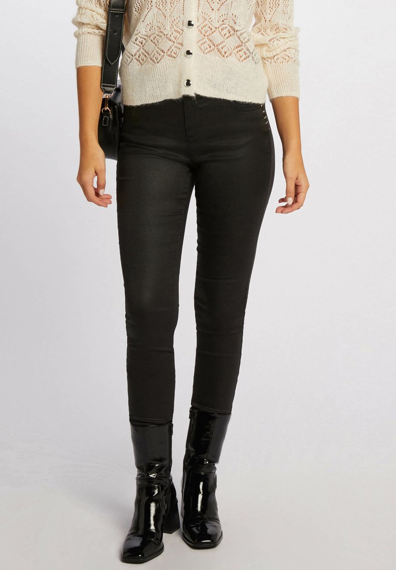 Jeans skinny neri in tessuto elasticizzato, con un design aderente. Abbinati a stivali neri in vernice al ginocchio per un look elegante.