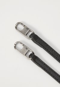 Cinghie in pelle nera con clip metalliche. Le cinghie presentano una superficie liscia e cuciture visibili, con una finitura opaca sull'hardware.