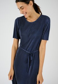 Vestido navy de manga corta, con un patrón de puntos blancos, escote redondo y detalle de cintura anudada. Tejido suave con un ajuste relajado.