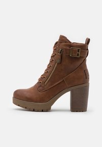 Bottes marron à la cheville avec un talon haut épais. Elles présentent une fermeture éclair à l'avant, un laçage et une boucle décorative sur le côté. Surface texturée.