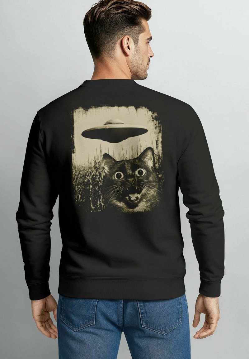 Black sweatshirt featuring a cat's face with large eyes, surprised expression, and a UFO above, all in a distressed beige print.