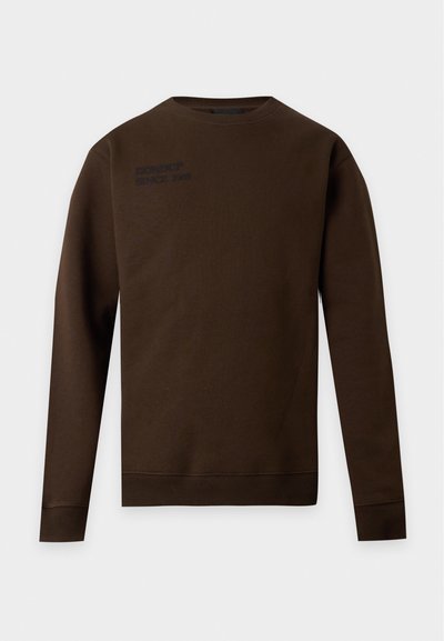 Sweat-shirt marron à manches longues et col rond avec un texte noir discret sur le haut gauche de la poitrine, poignets et ourlet côtelés, présenté sur fond blanc.