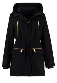 Zwarte capuchonjas met gouden ritsen, voorzien van een getailleerde taille, twee zijzakken en geribbelde manchetten. Gladde textuur en klassiek ontwerp.