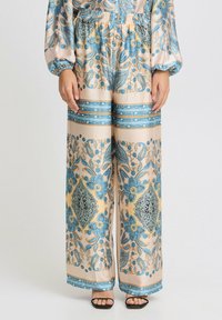 Weit geschnittene Hose aus seidig weichem Stoff mit einem Blumen- und Paisleymuster in Blau- und Beigetönen, elastischem Bund und blauen Akzenten.